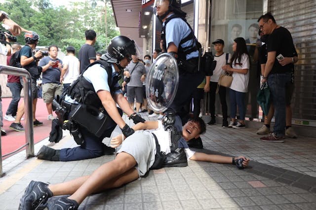 警員把示威者制服在地上。