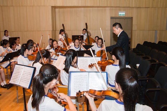 梁建楓指揮拔萃女書院學生演奏樂章。（樂團提供）