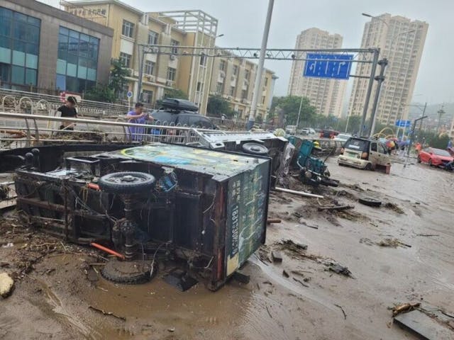 大水過後，北京門頭溝區一片泥濘，被沖毀的車輛橫臥在馬路上。（亞新社）