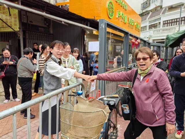 香港團友（右）在中英街隔着圍欄向深圳境內同胞握手。