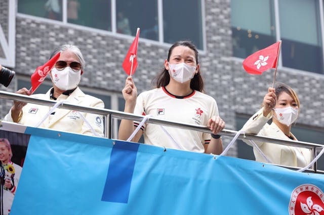 凱旋歸來的香港奧運代表隊參加花車巡遊，圖為（左起）霍震霆、何詩蓓和劉慕裳向市民揮旗致意。（亞新社）