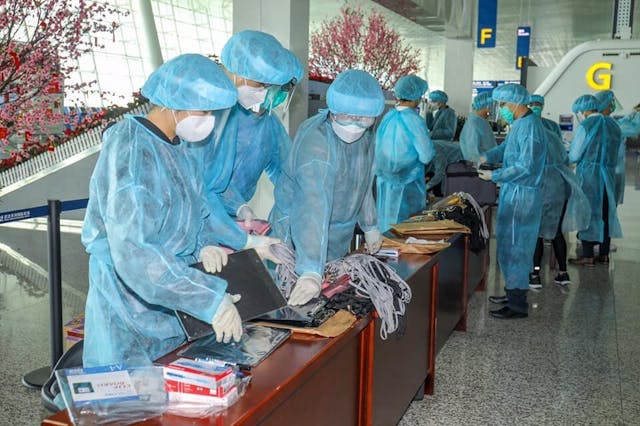 乘客中午前陸續抵達武漢天河國際機場，由現場人員核對資料，並派發識別牌及登機證。（亞新社）