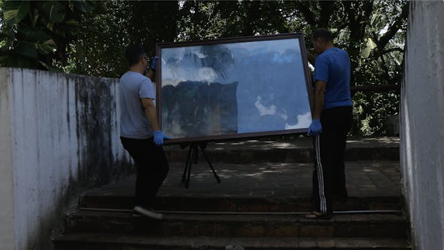 張偉民在巴西小鎮美術館的地下室中，找到了張大千的佳作《瑞士雪山》，兩個工人抬着這幅畫到室外。