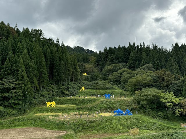 遠眺農舞台，雕塑、金黃稻田、訪客和忙碌的農人自然和諧。