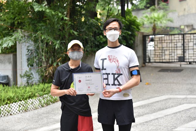 作者（左）參加「九龍城文化飛步遊嘉賓試跑日」，文物保育專員蔣志豪（右）頒發感謝狀給他。