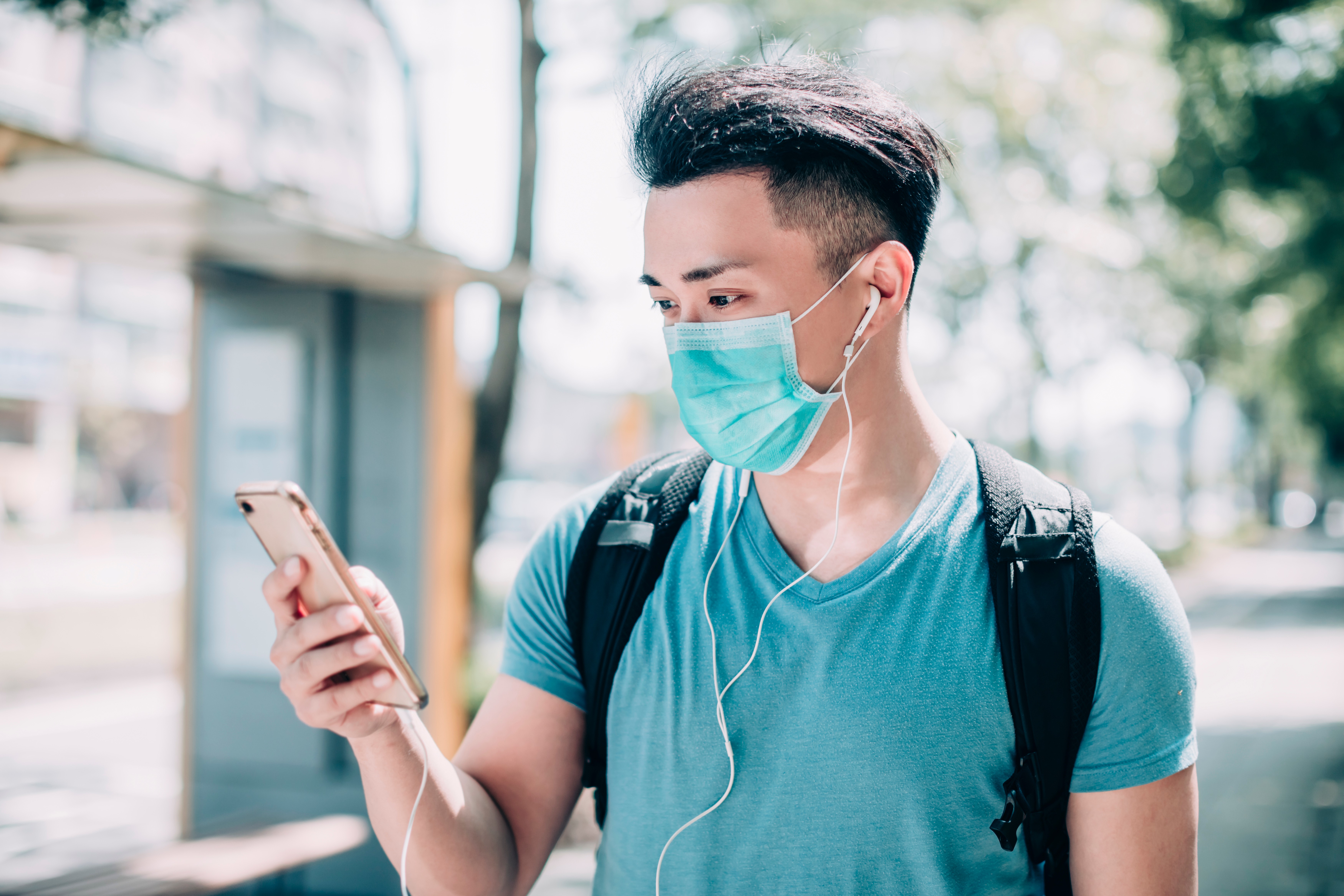 Young,Man,Wear,Mask,And,Walking,On,Street,Using,Mobile